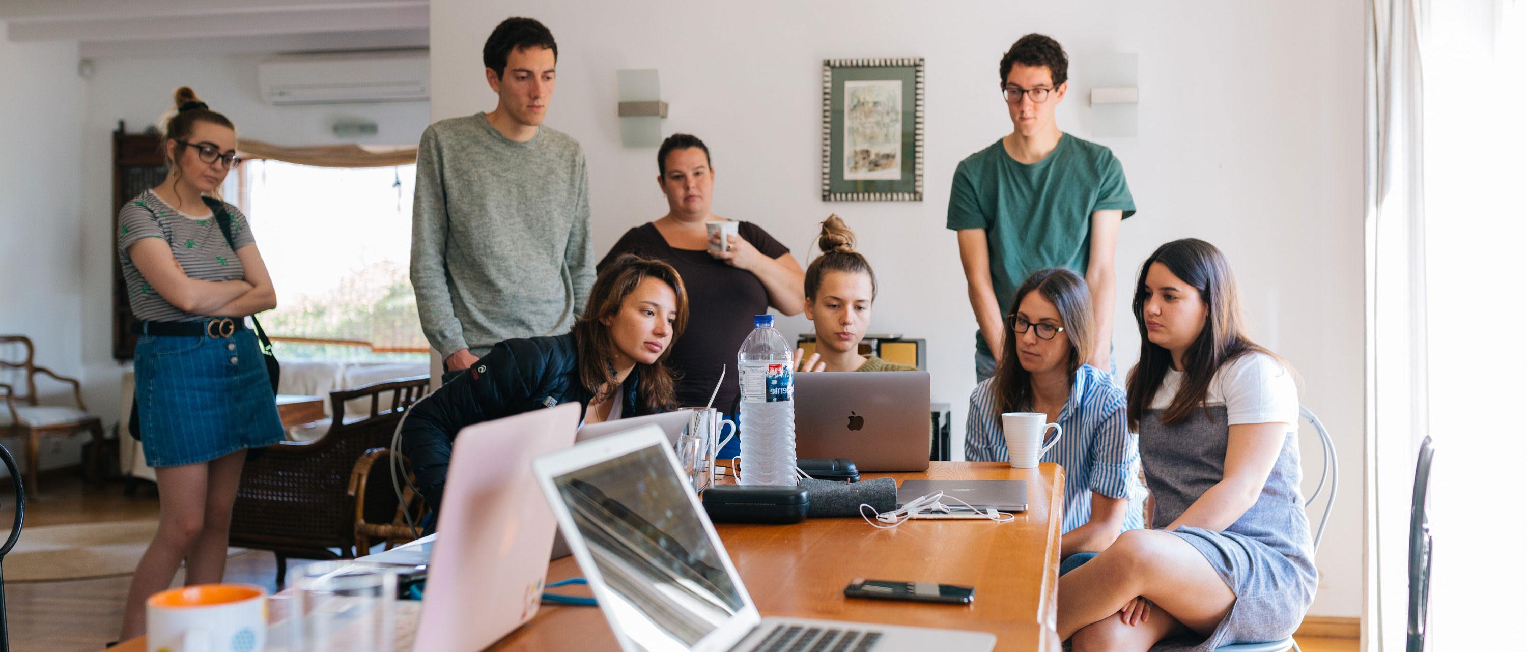 Group of people standing around a computer